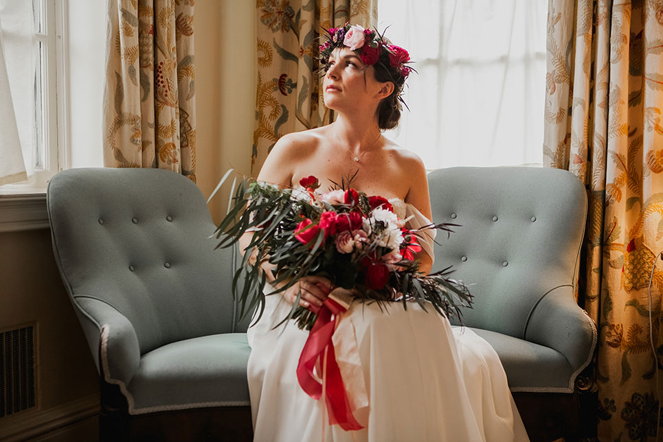 bride sitting in a hotel room with a beautiful bouquet and crown on her head waiting for the moment of the first look