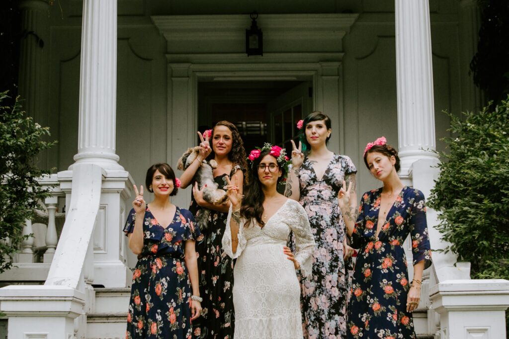bridal party posing for photos with a background of a house