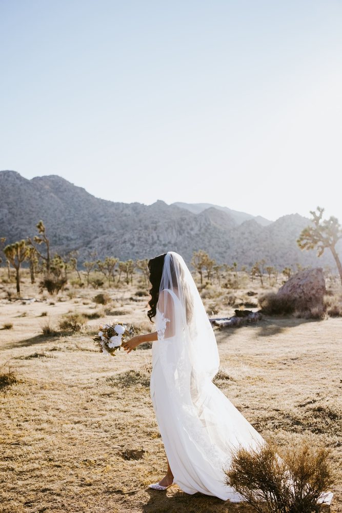 Bride walking through the Joshua trees with her bouquet