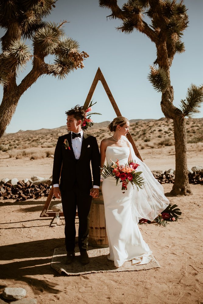 Couple at a triangle ceremony arch between Joshua trees
