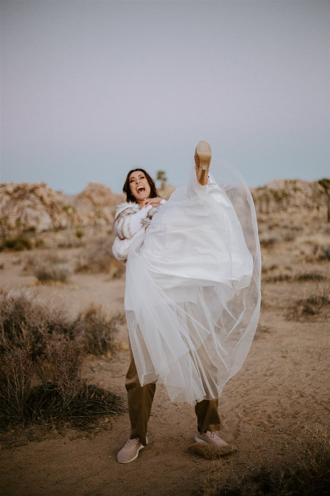 Bride kicking her heel up in her groom’s arms