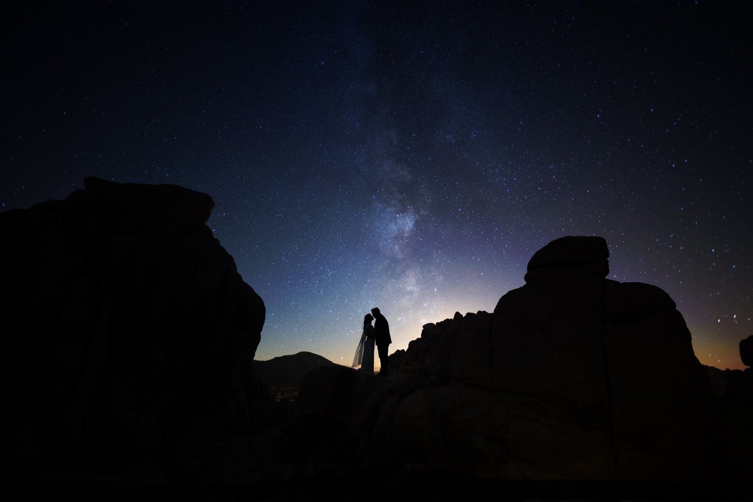 Couple between boulders under the Milky Way