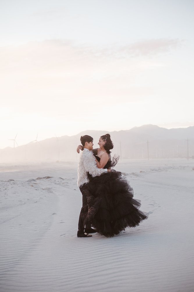 Couple embracing among the wind turbines at sunset