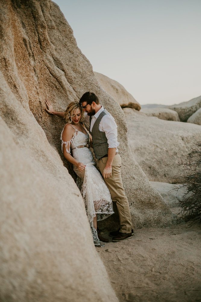 Couple leaning against a boulder at sunset