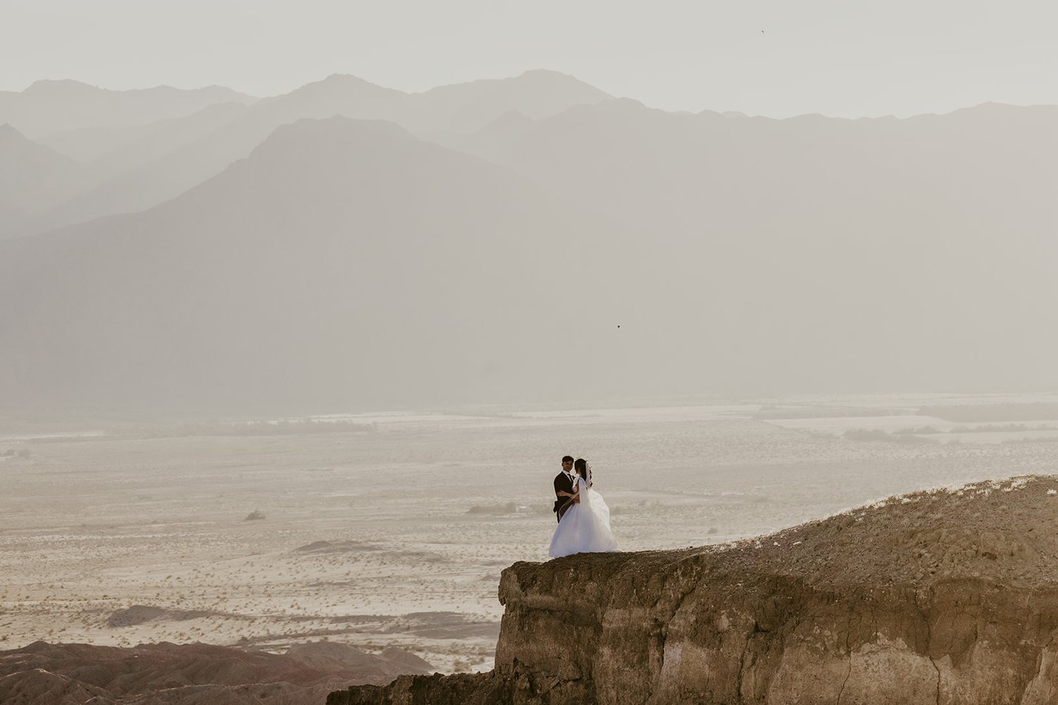 Couple on a cliff edge above the desert haze