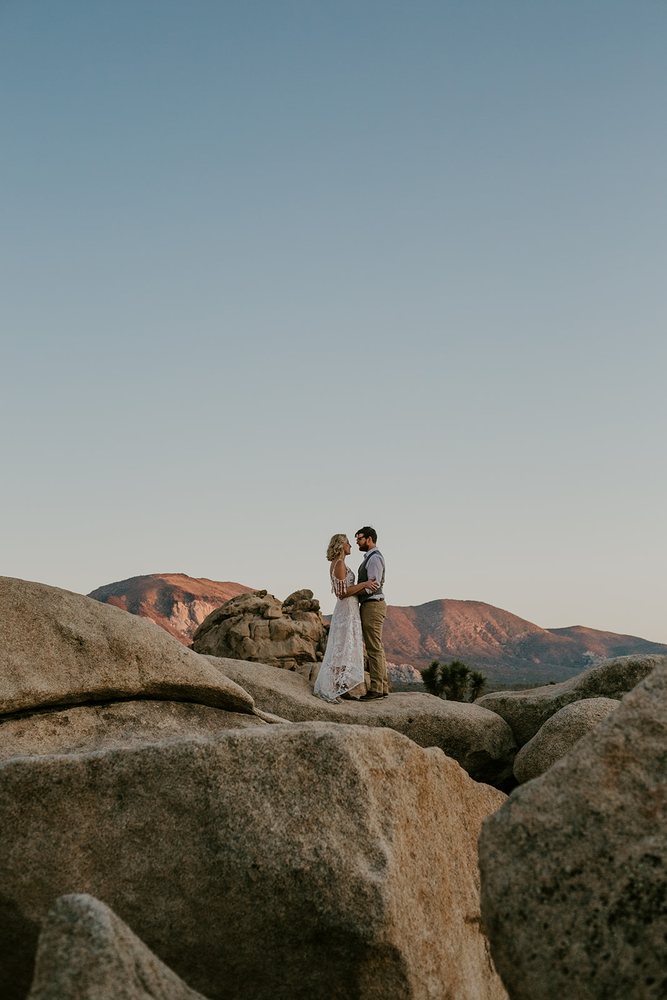 Couple on the boulders with pink mountains behind
