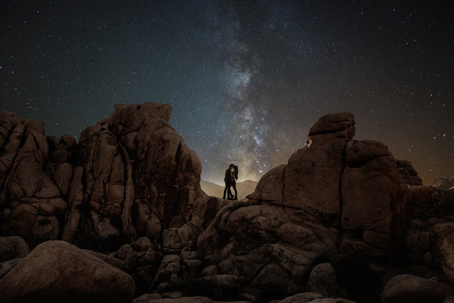 Couple on the rocks under the Milky Way