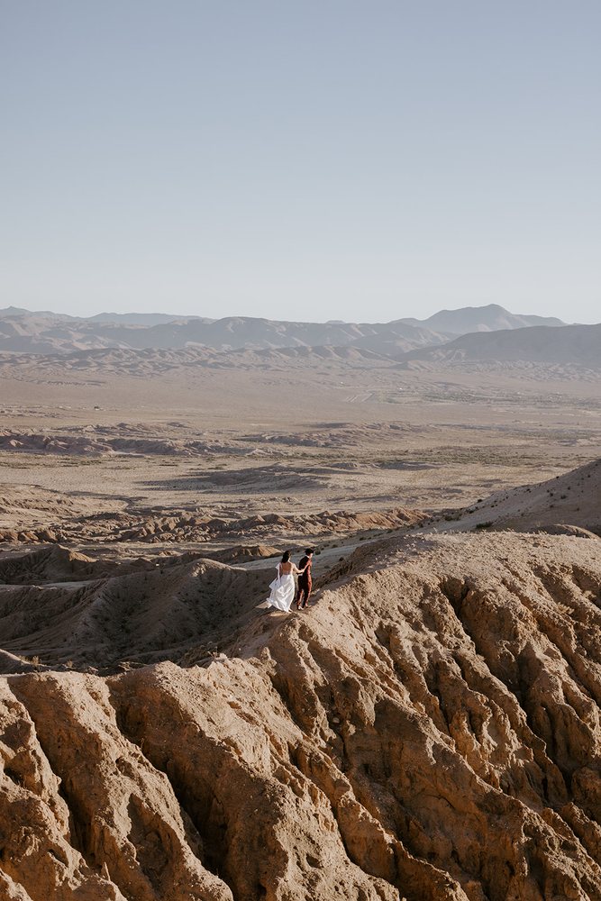 Couple standing on a desert ridge with the valley below