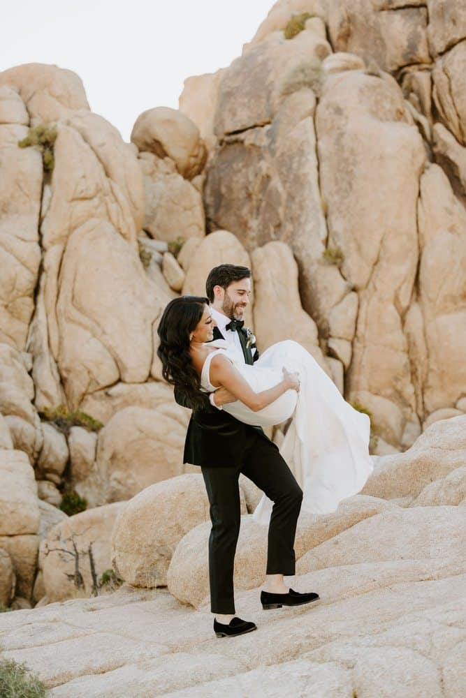 Groom carrying his bride across the rocks