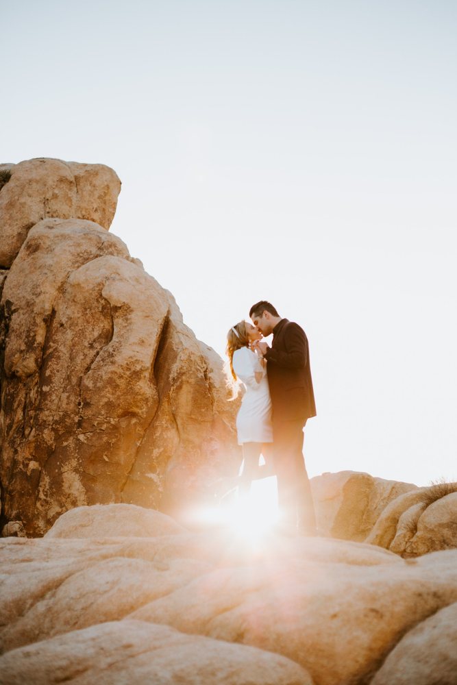 Kiss on the boulders with the sun flaring through