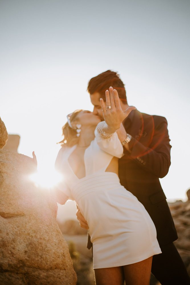 Kiss with the sun flaring behind the boulders
