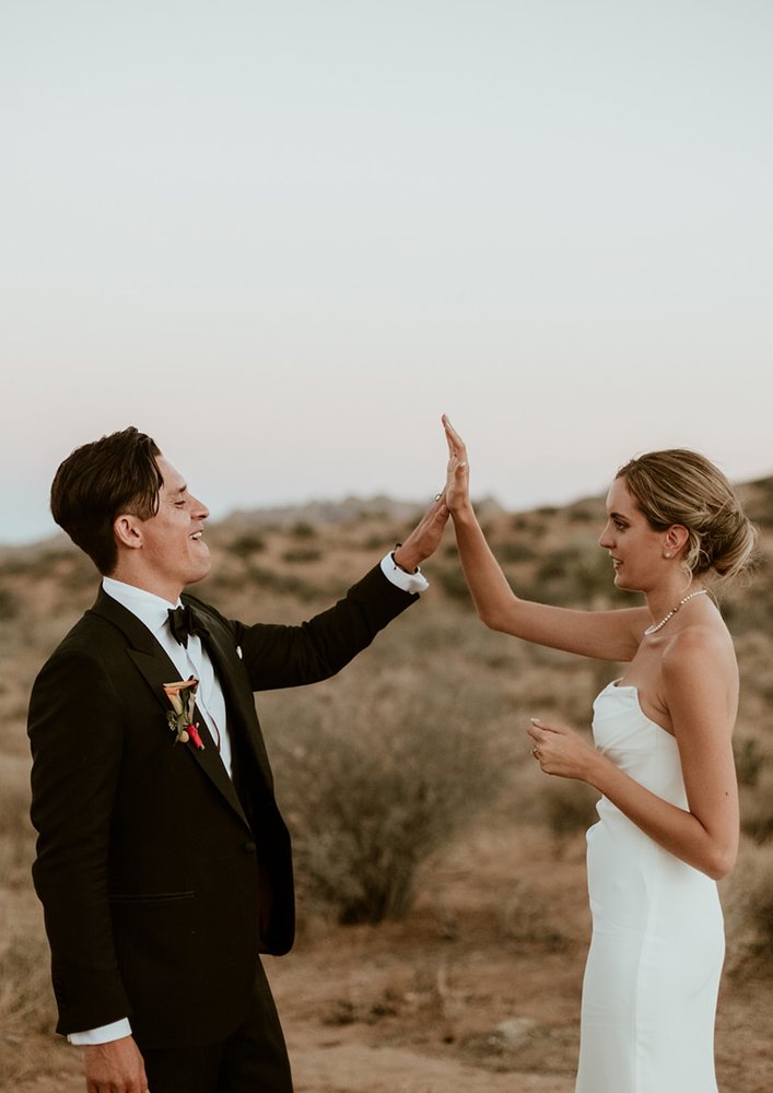 Newlyweds high-five in the desert