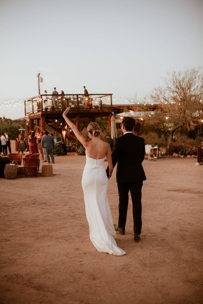 Newlyweds walking toward their desert reception